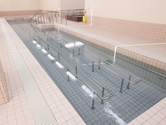 長細いプールには水中に手すりがたくさんつき、出入り口には手すり付きのスロープが設置されている。