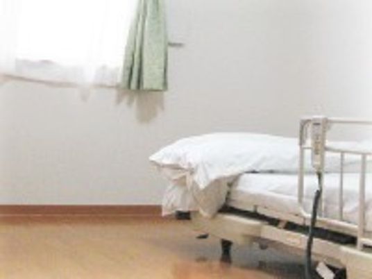ベッドには寝具がセットされ、窓にはグリーンのカーテンが付いている。