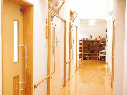 個室のドアが続く廊下の様子。奥のほうにげた箱がある施設エントランスがある
