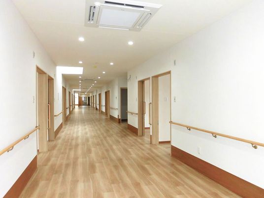 手すりがついた廊下の様子。両側に個室のドアがある幅が広い廊下