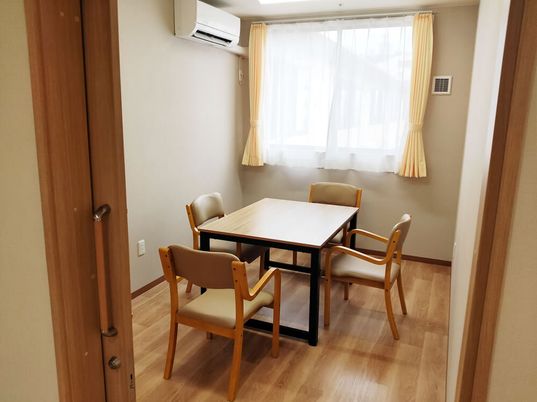 小さなテーブルと椅子が４脚並べられている施設内の談話室の様子