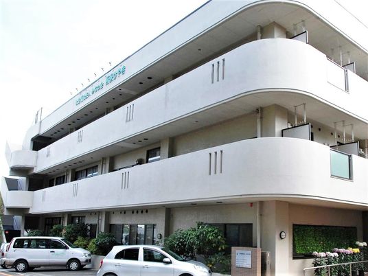 3階建ての建物は白を基調としていて、ベランダが各フロアにつき、屋外階段も設置されている。