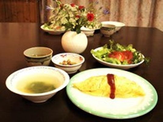 オムライスにスープやサラダなどが並ぶ食卓には花も添えられ、雰囲気がある。