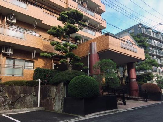 レンガ調の外壁が明るい雰囲気の5階建ての建物。周辺には緑が多くある。