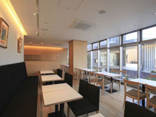 一面が窓となっていて明るいカフェにはシンプルないすやソファ、テーブルが並べられている。