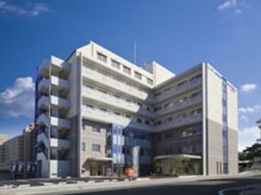 青い空の下にある7階建ての大きな建物は白とグレーでまとめられ、スタイリッシュな外観。