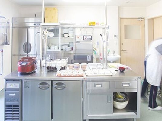 広めのキッチンのような場所に冷蔵庫と炊飯器などが置いてある様子