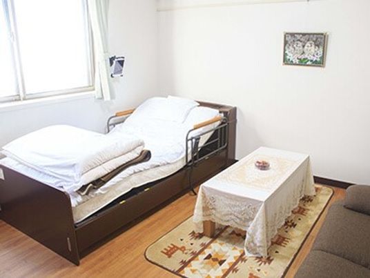 介護用ベッドや机が写っている一人用の部屋。緊急コールが取り付けてある