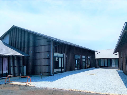 木造の建物は平屋建てで重厚感のある外観。三角屋根が付き、コの字型の建物の中央には庭のような広いスペースがある。