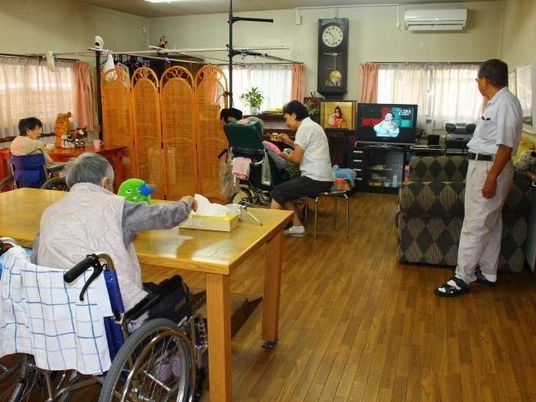 入居者とスタッフが広い共有スペースで思い思いの場所で過ごしている。