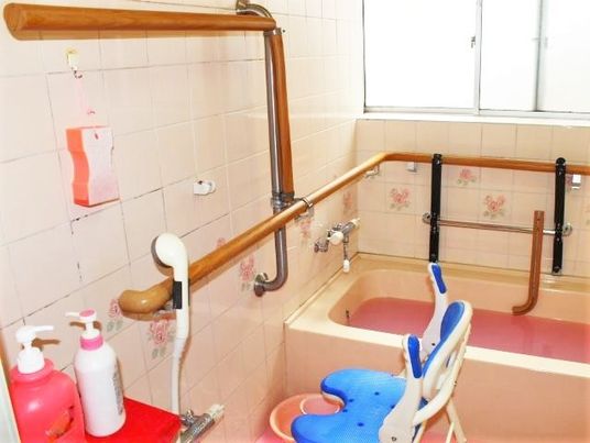 手すりやシャワーなどが設置された浴室には花柄のタイルが貼られている。