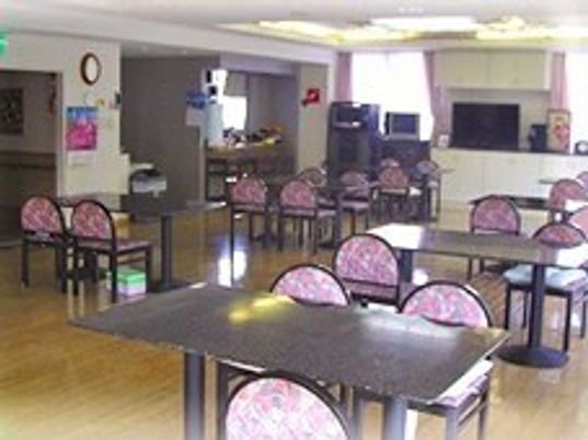 木製のダイニングテーブルが複数置かれ他フローリングの食堂には、テレビやカラオケセットもある。