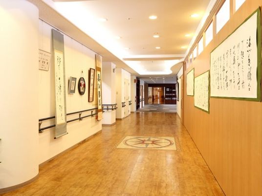 まっすぐに続く廊下に書道が飾られている様子。手すりが取り付けられた廊下