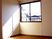 カーテンが付いていない大きな窓が設置されている部屋には家具や家電はない。フロアはフローリング。