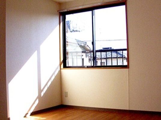 カーテンが付いていない大きな窓が設置されている部屋には家具や家電はない。フロアはフローリング。