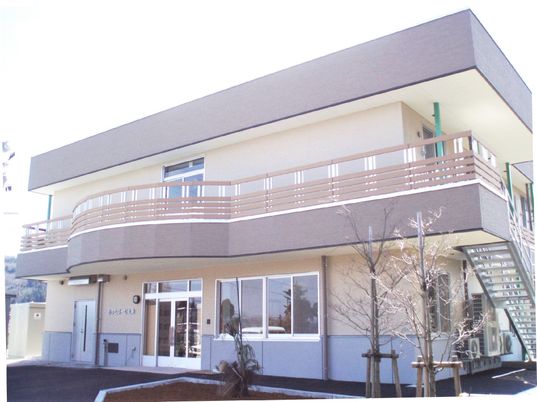 2階建ての建物はベランダや屋外階段が付き、ベージュやブラウンでまとめられている。