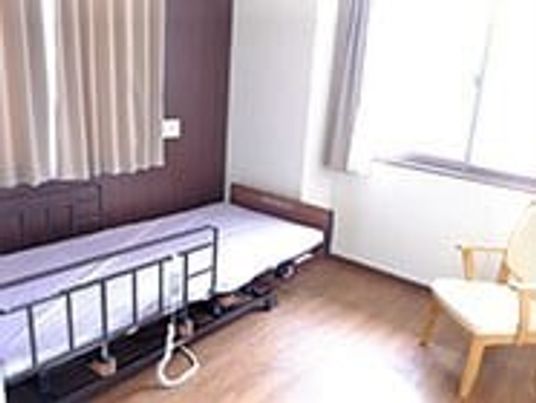 介護用ベッドやいすが置かれたフローリングの居室には大きな窓が付いている。