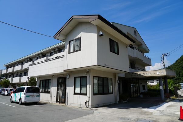 じゅうたんが敷かれた居室にはベッドやテレビなどが置かれ、大きな窓にはカーテンがかけられている。