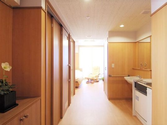 開放的で広めの居室の様子。右側にキッチン、左側に収納やトイレがある様子