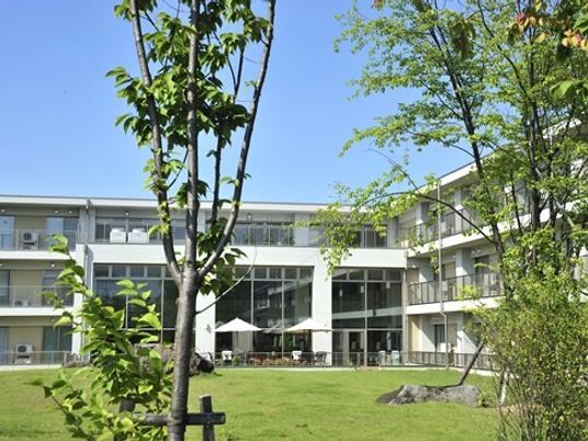 施設内にある中庭の様子。手前に芝生と木々が植えてあり、奥の方に建物がある