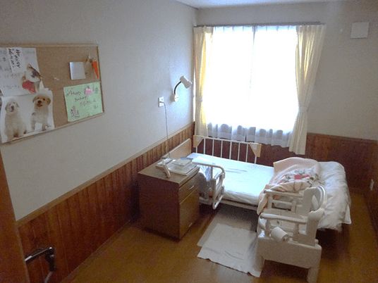 介護用ベッドと椅子、物入などが置いてある施設内の居室の様子