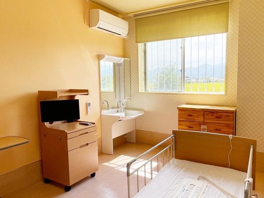 エアコンや洗面所、タンス、介護ベッドなどが置かれた部屋には大きな窓があり、外の景色が見える。
