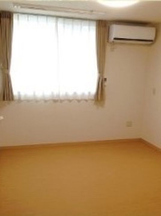 エアコンや窓が付いている小さ目の部屋。施設内の居室の写真