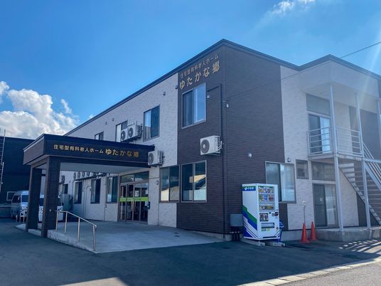 ２階建ての建物は玄関先には手すり付きのスロープがあり、側面には屋外階段が付いている。