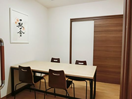 机が1つと椅子が4つ並べられている、落ち着いた相談室