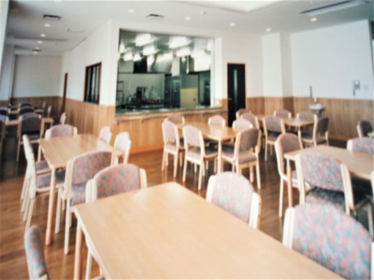 食堂にはたくさんのダイニングテーブルが並び、奥には厨房もある。