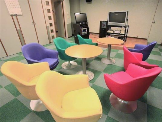 カラフルな椅子が並んでいる施設内のリラックススペース。カラオケ設備がある様子
