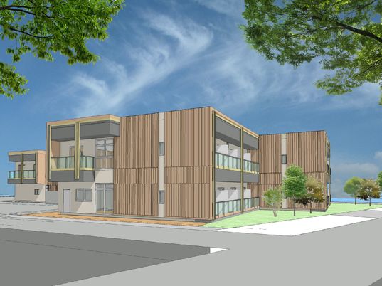 ブラウン系の外観の２階建ての建物の周りには草木が植えられた庭があり、各フロアにベランダが付いている。
