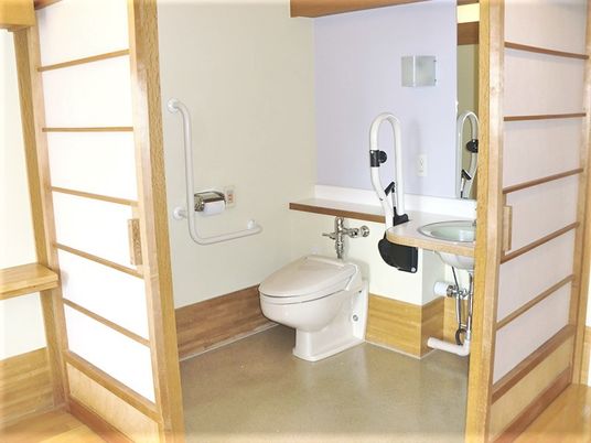 緊急コールや手すりがある障子仕切りのトイレ。施設内のトイレの写真