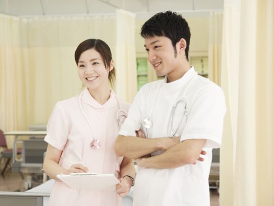 患者の様子を見ながら何かについて話し合う看護師と医師。リラックスしている表情