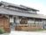 グレーの瓦屋根が付いた平屋建ての建物。平屋建ての建物は一部2階建てで庭もある。