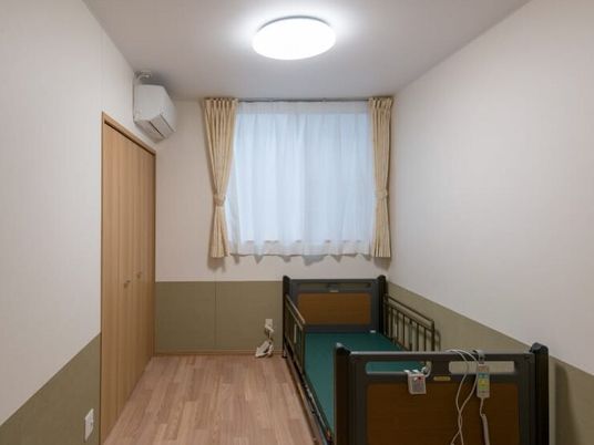 シンプルな部屋にエアコンとベッドが置いてある様子。施設内の居室の写真