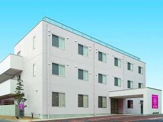 四角い無駄のない建物の外観。エントランス部分に車用の雨除けが付いている