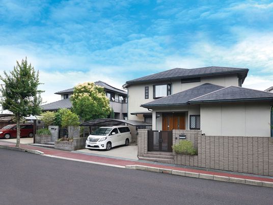 グレーの屋根が付いた２階建ての建物は敷地内には駐車場があり、車が止まっている。