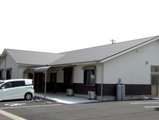 平屋建てに近い住宅のような建物。広めの駐車場スペースが確保してある様子