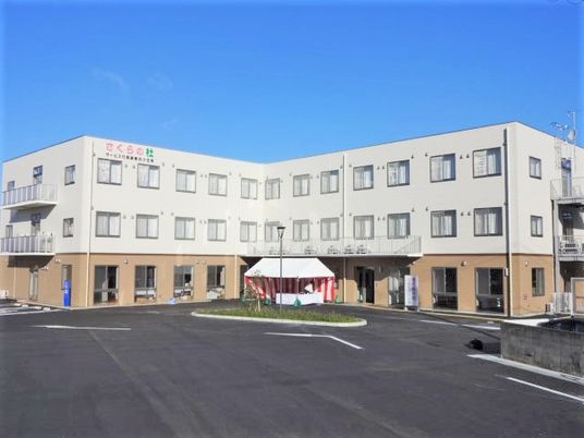 ３階建ての建物がある敷地内には駐車スペースもあり、１階部分はブラウンの外壁。
