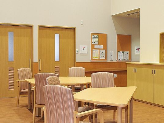 木のぬくもりを感じられる施設内の共有スペース。四人掛けの椅子とテーブルが置いてあるスペース