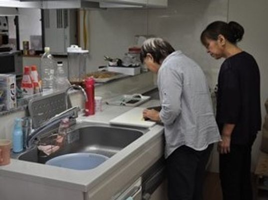 生活リハビリの一環で料理に取り組んでいる高齢者とそれを見守るスタッフ