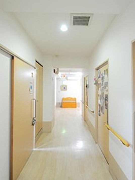 両サイドに手すりが設置され、居室ドアには写真がたくさんつけられている。