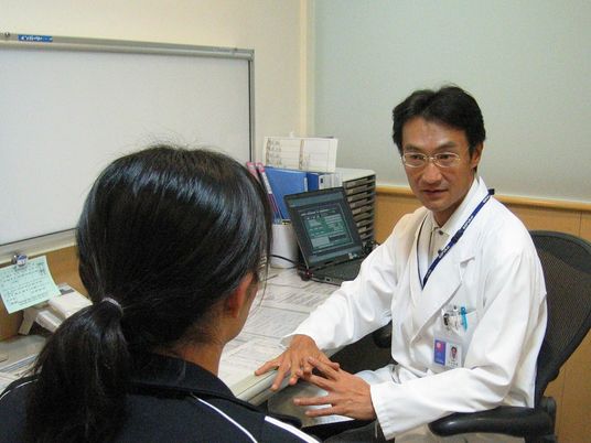 病院の男性医師が利用者の相談に乗っている様子
