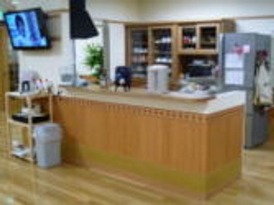 対面キッチンの奥には冷蔵庫や食器棚が置かれ、壁掛けテレビなどが置かれている。