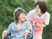 車いすの高齢女性と付き添いのピンクのエプロンを付けた若い女性スタッフが楽しそうに散歩をしている。