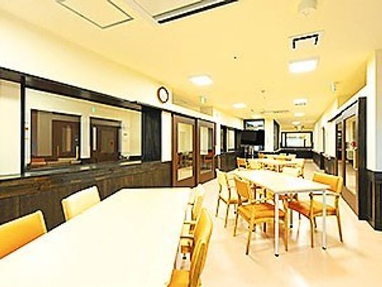 複数のダイニングテーブルが置かれた明るい食堂。テレビも設置されている。