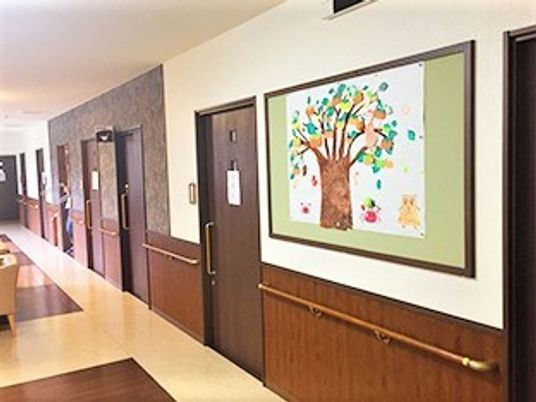 絵画が掲げられている施設の廊下の様子。手すりがついている清潔な様子の廊下