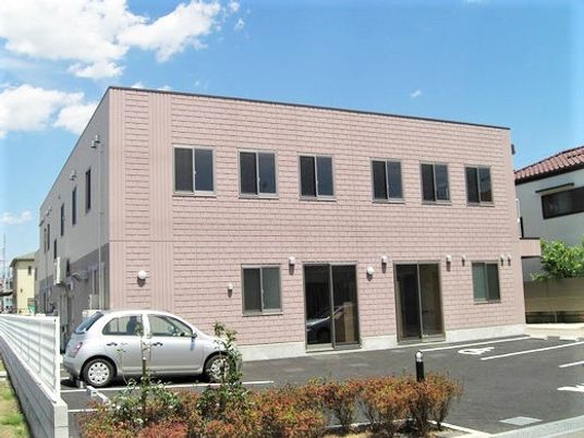 2階建ての四角い建物はベージュで駐車場もあり、入り口が二つある。