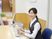 建物内で仕事をしているスタッフ。誰かに目線を合わせ、会話しようとしている。